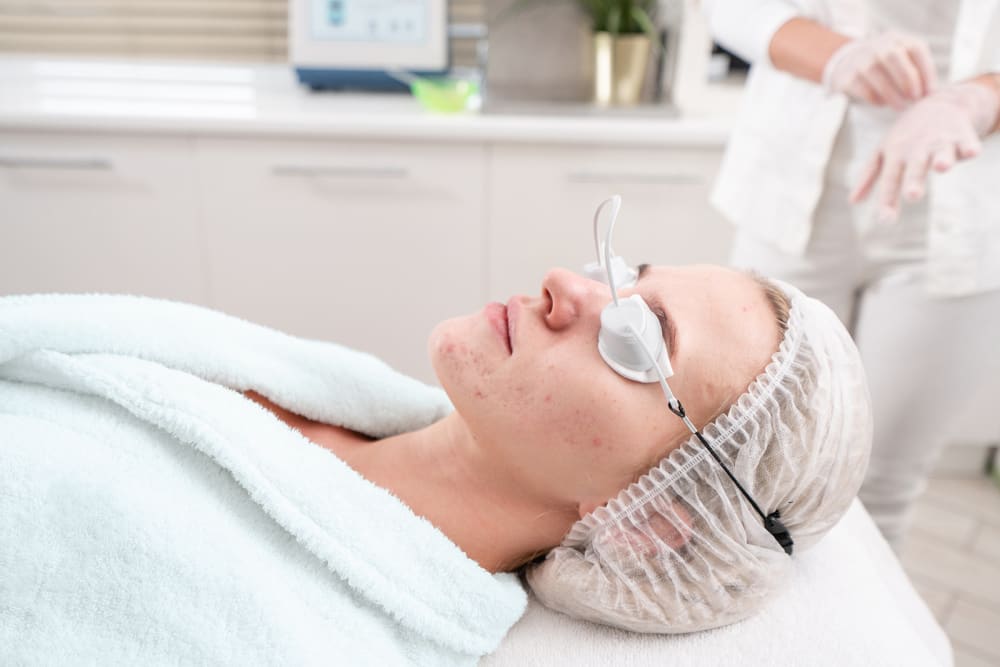 What treatment is best for acne scars? In this image there is a lady lying on a treatment bed preparing for Aviclear laser treatment. She is wearing a comfortable robe, eye protection and looks very relaxed.