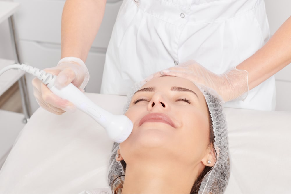 Medical Aesthetician performing RF skin tightening on a young woman's back to remove tattoo with reduced risk of scarring.
